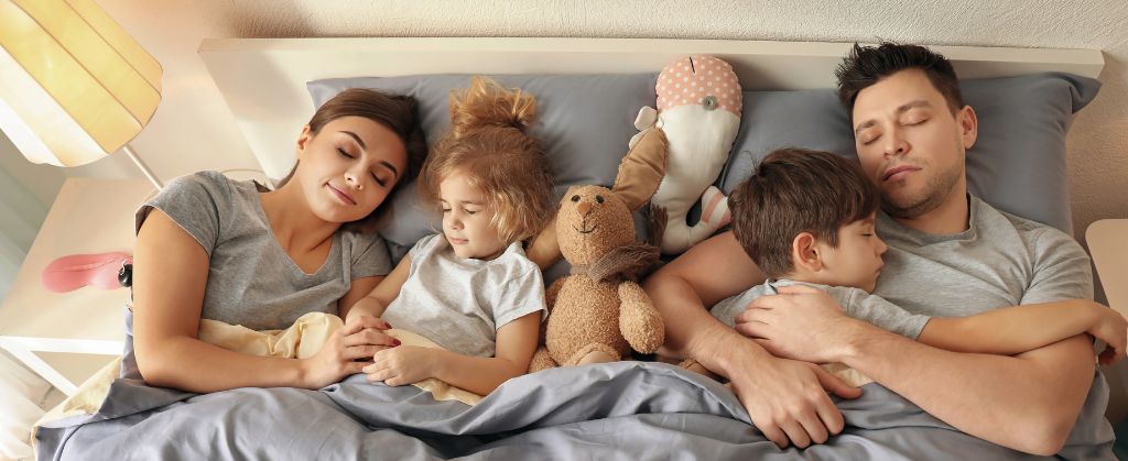 Mom with kids and dad resting in bed